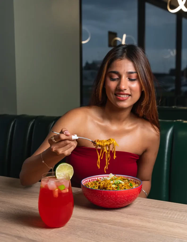 Woman enjoying a bowl of noodles and a refreshing drink