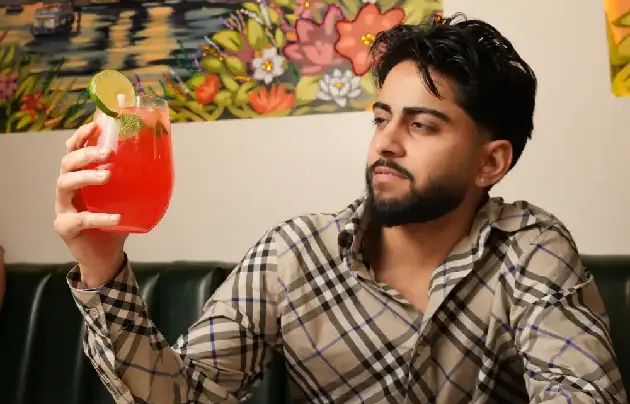 Man admiring his red fruit cocktail at Bombay Canteen