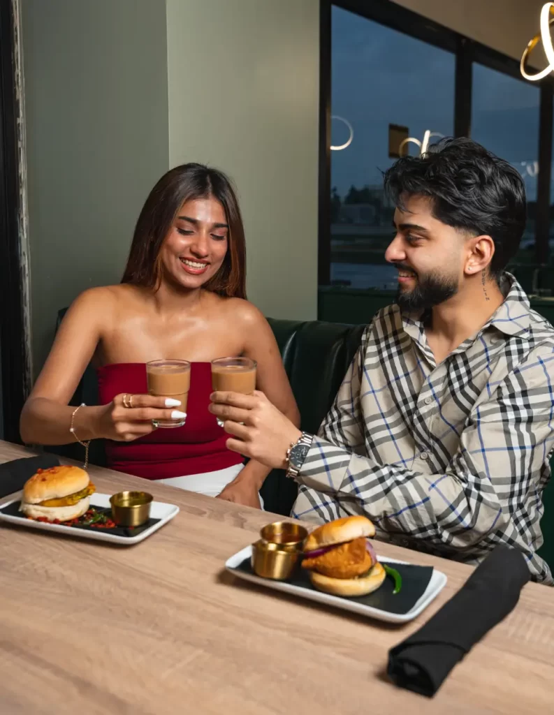 Couple enjoying cutting chai tea and Vada Pav at Bombay Canteen