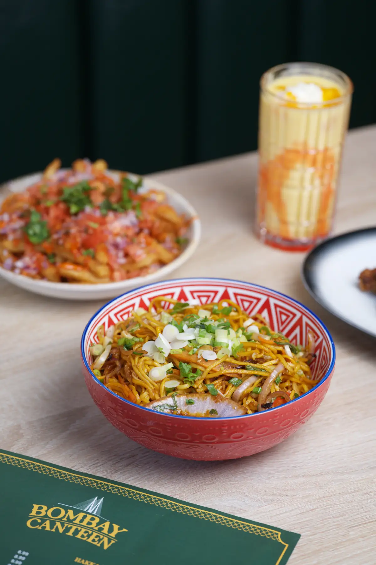 Bowl of Hakka Noodles served alongside a refreshing creamy Mango Lassi