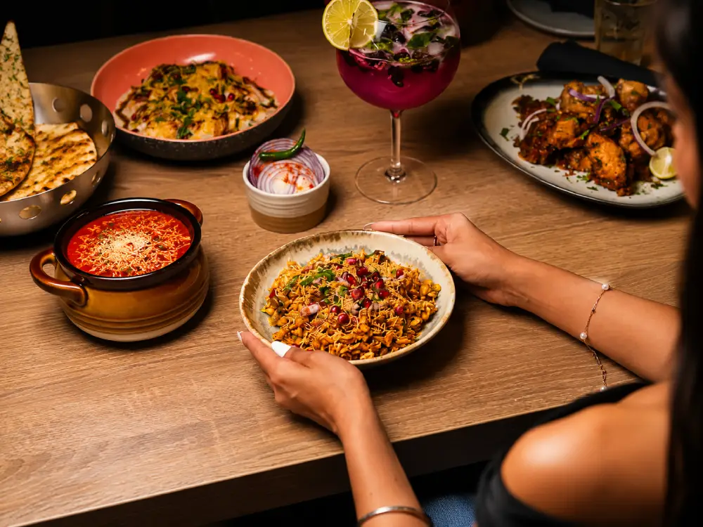 Guest holding a bowl of fresh Indian Chaat garnished with pomegranate